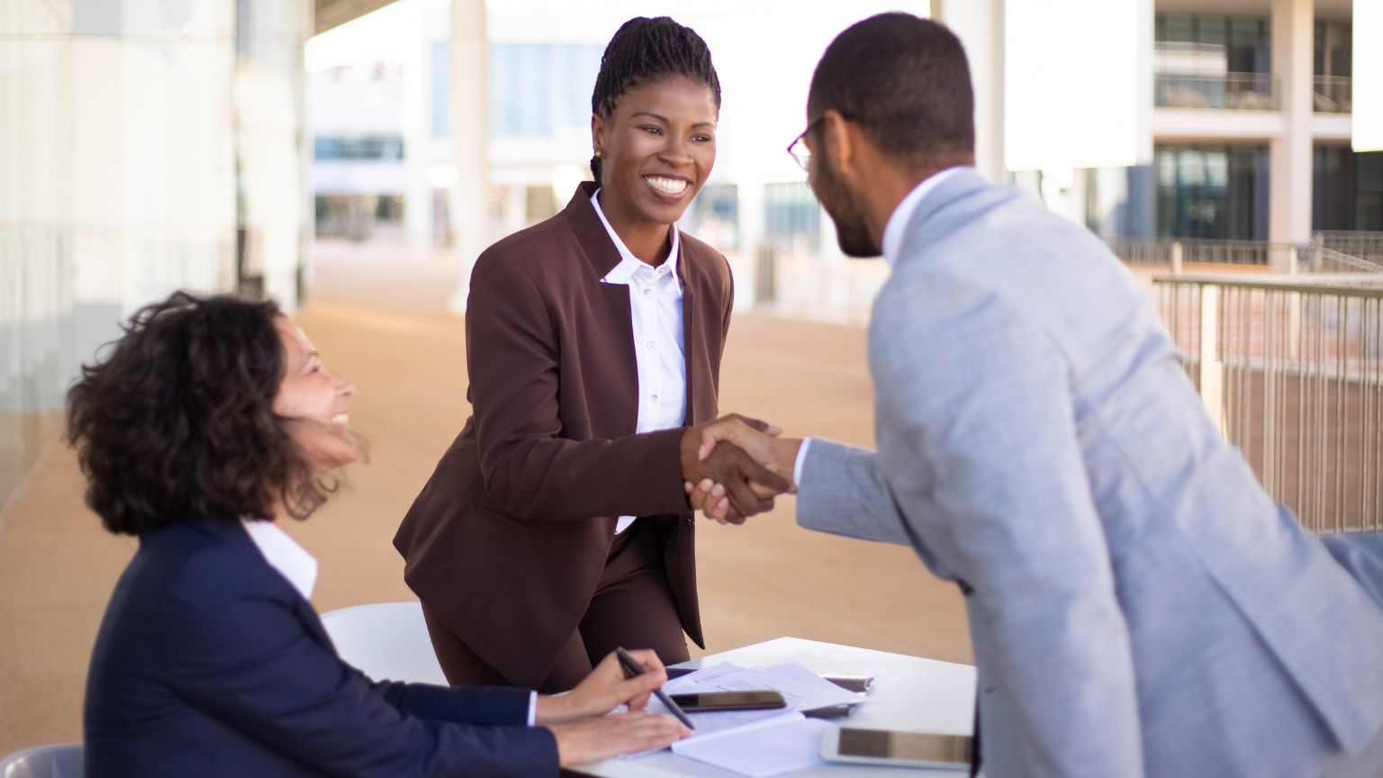 A woman and a man shaking hands in a corporate office